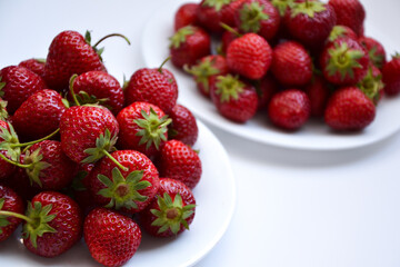 Strawberries on white plate. Freshly picked strawberry. Organic berries on white background. Village garden harvest.