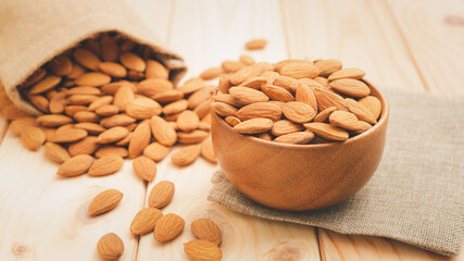 Almonds in brown wooden bowl with bag on wooden table background.Healthy food Concept.