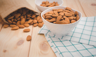 Almonds in white porcelain bowl with bag on wooden table background.Healthy food Concept.