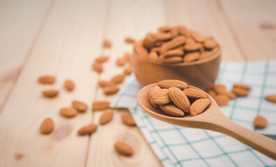 Almonds pour from wood spoon on wooden table background.Healthy food Concept.