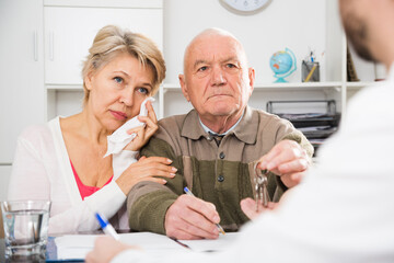 Elderly man and woman hand over keys on contract of sale apartments to agent