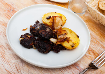 Fried rustic tasty blood sausage with potato served at plate, nobody