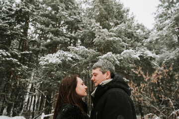 Adult man and woman on the background of a winter snow-covered pine forest