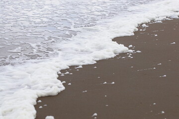 closeup of sea line with foam, foamy water at the black sand beach