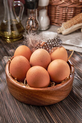 Brown chicken eggs close-up in a wooden bowl, organic protein of natural origin, free space for text.