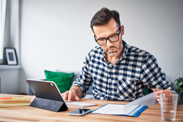 Busy man doing paperwork while working from home
