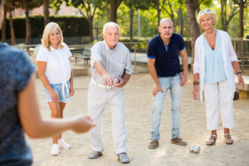 Smilig mature people playing petanque together in park outdoor