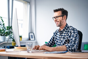 Smiling freelancer working on computer from home office