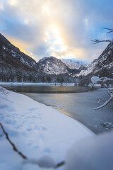 Winter landscape with frosty lake, snowy trees and mountains. Buntautal and Bluntausee.