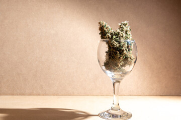 Medical marihuana buds inside a crystal glass. In brown background with selective focus.