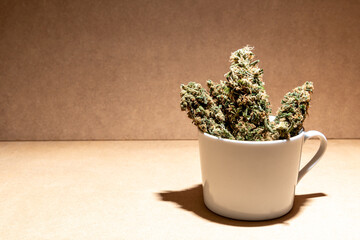 Ready to consume medical marihuana buds inside a coffee cup. Selective focus.