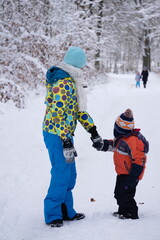 Fototapeta na wymiar Children walking and playing in the snow forest