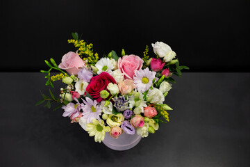 A bouquet of flowers in decorative packaging on a dark background.
