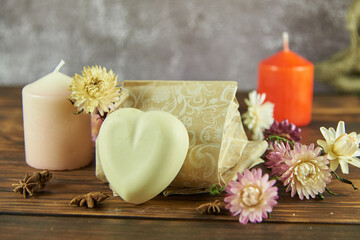 Natural handmade skincare. Handmade natural soap, candles and flowers on the dark wooden countertop.