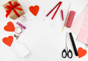Valentine's Day. Making a sub-cancer for the holiday with your own hands from paper. View from above on the white table, scissors, red hearts, gift.
