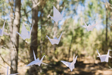 White Origami folded birds hanging in trees