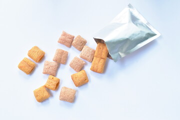 colorful crispy biscuit stuffed cream pouring from aluminium foil package on white background