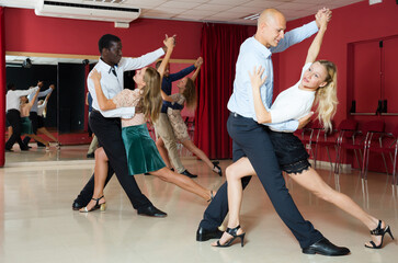 Young smiling people practicing passionate samba in dance class..