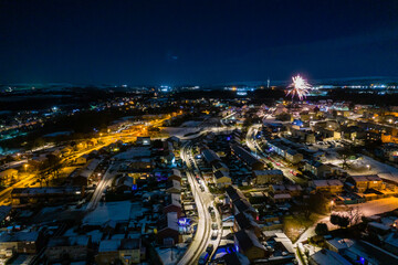 Aerial view of fireworks over a small, snow covered town celebrating New Years Eve