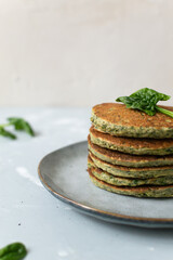 Spinach and banana pancakes and green leaves on a gray plate on a gray background. Healthy food concept. Copy space. Vertical orientation.