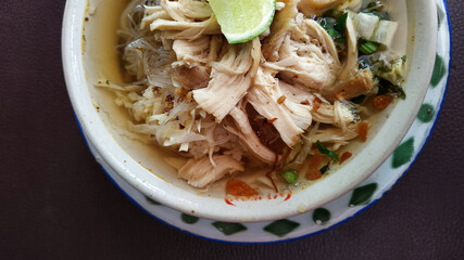 Soto ayam. Fresh chicken soup with warm sauce and a sprinkling of chicken pieces plus lime slices