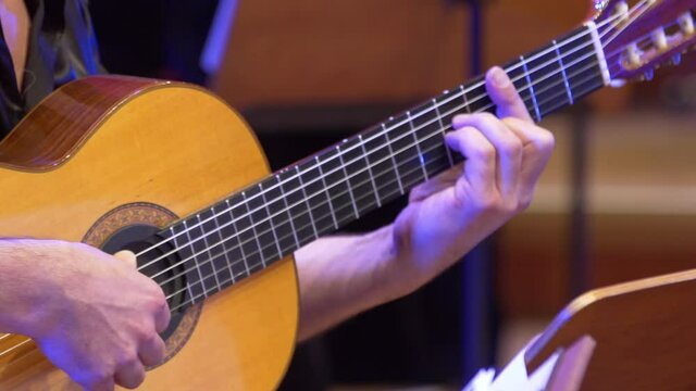 Guitar player plays on a classical guitar. Close-up of a Spanish acoustic guitar and a Bandoneon accordion playing while a music show on stage. Tango melody philharmonic orchestra.