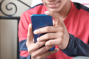 unrecognized young man sitting on bed using smart phone.