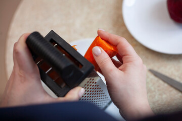 A young woman is rubbing a carrot. Cooking Ukrainian borscht step by step