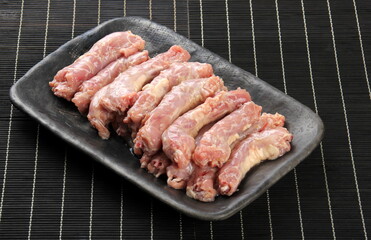 Raw Chicken neck skinless on a clay plate, Black bamboo napkin in the background