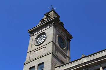 Obraz premium A Town Hall Clock and tower in Welshpool, Powys, Wales, set against a blue sky.