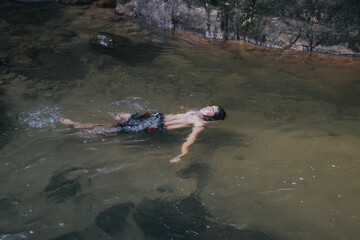 A male traveler in the rain forest pool stream or waterfall.Healthy and active lifestyle.Camping and hiking.
