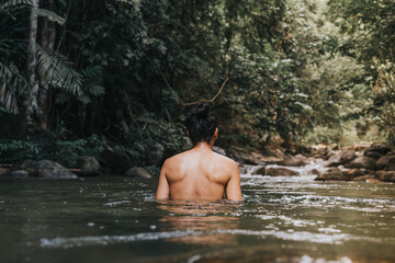 A male traveler in the rain forest pool stream or waterfall.Healthy and active lifestyle.Camping and hiking.