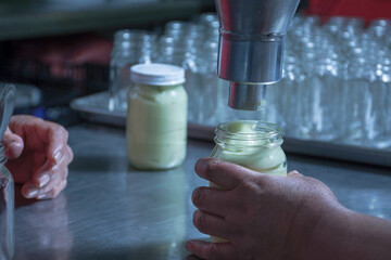 Pouring processed mayonnaise into a glass jar