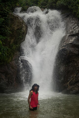 An asian male traveler enjoying the beauty of rainforest waterfall.A male explorer in the waterfall pool.Camping and hiking lifestyle.Into the wild.