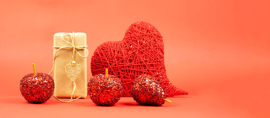  Gift in craft paper with a heart made of red threads, decorative red fruits on a red background