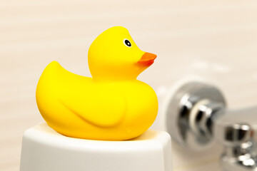 bright yellow toy duckling on a white stand in the bathroom on a light background