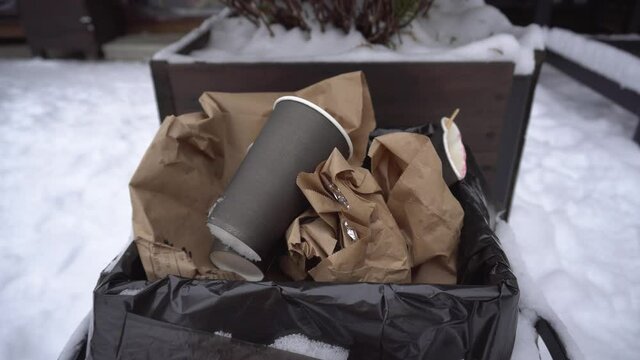 Used coffee cup in the trash can female hand throws out trash, protection of nature, ecology