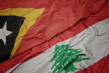 waving colorful flag of lebanon and national flag of east timor.