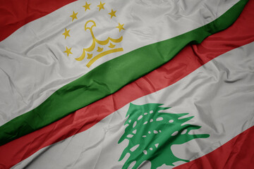 waving colorful flag of lebanon and national flag of tajikistan.