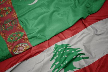 waving colorful flag of lebanon and national flag of turkmenistan.