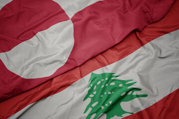 waving colorful flag of lebanon and national flag of greenland.