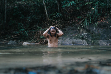 A male traveler in the rain forest pool stream or waterfall.View from behind.Healthy and active lifestyle.Camping and hiking.