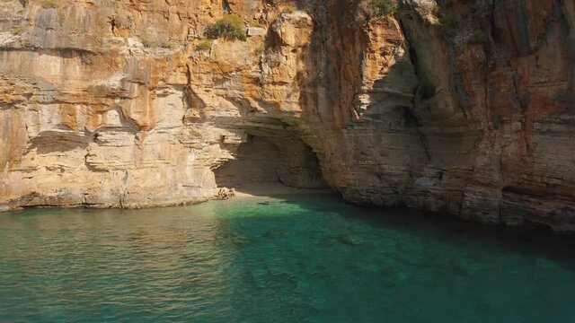 Tourist people relax in a hidden cove with a cave in mountain on the road from Demre to Antalya, Turkey. Aerial view 4K.