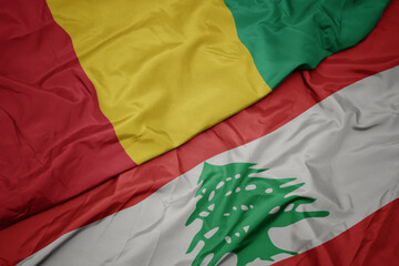 waving colorful flag of lebanon and national flag of guinea.
