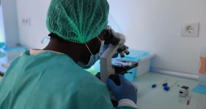 African medical worker in hazmat suit working with  micoroscope inside laboratory hospital during coronavirus outbreak