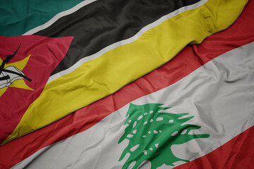 waving colorful flag of lebanon and national flag of mozambique.
