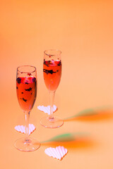 Two Champagne glasses on the orange background with colorful 3d shadows. Composition for Valentine's day	