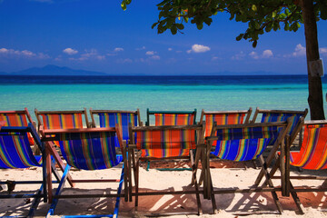 View on isolated colorful empty deck chairs in a row on tropical beach, Thailand, Ko Phi Phi - tourism industry perspective concept