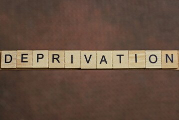 gray word deprivation made of wooden square letters on brown background
