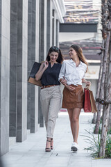 Young shopaholic friends women friends walking and carry shopping bags in the street city with happy and smiling.